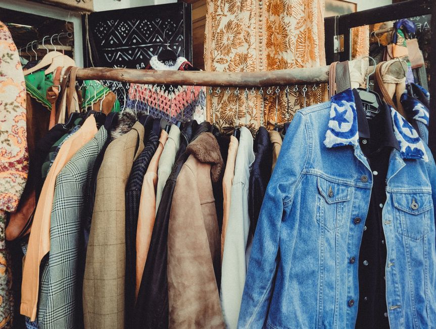 Pile de vêtements d'occasion triés avant mise en vente en ligne, smartphone posé à côté pour les photos