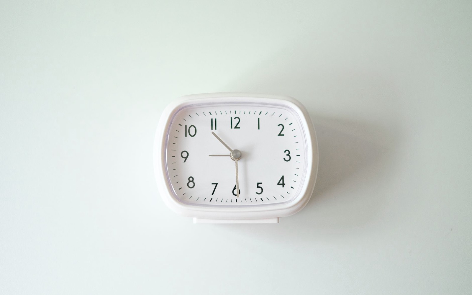 Horloge murale au-dessus d'un poste de travail, symbole du temps perdu sur les tâches répétitives en entreprise