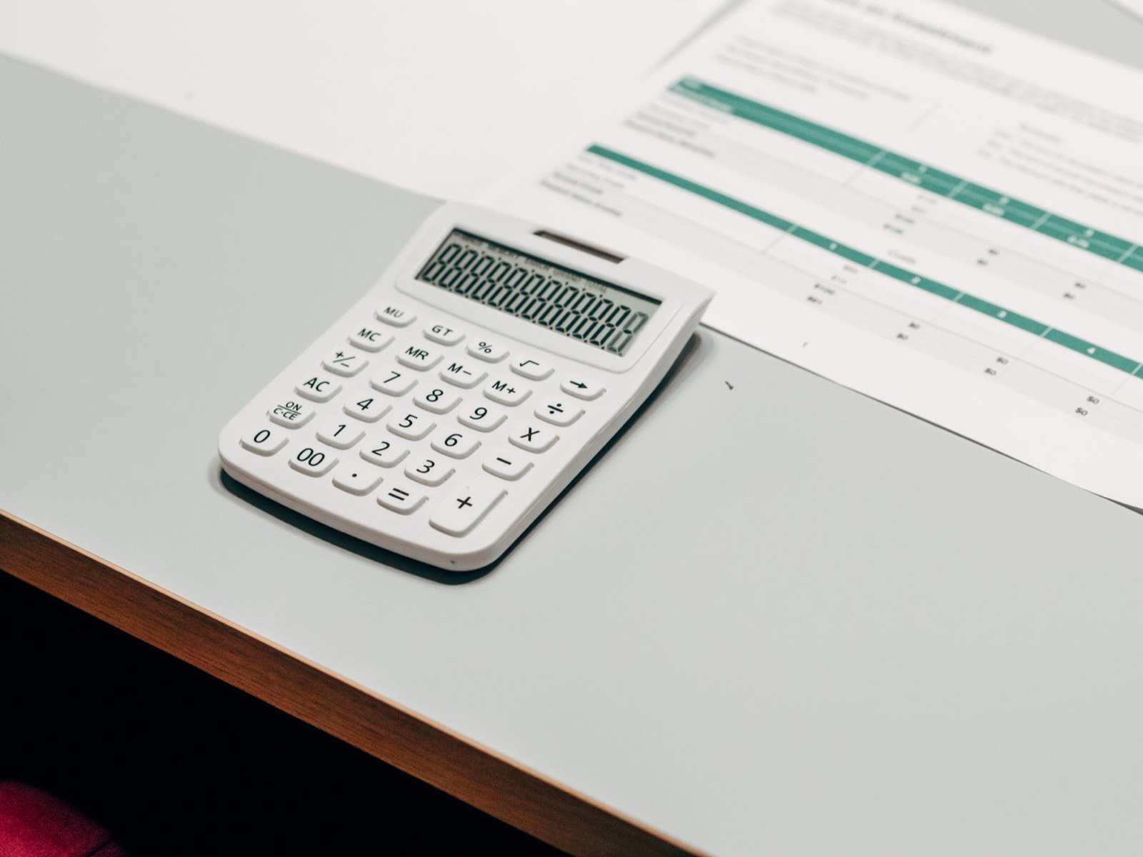 Factures, calculatrice et tableur sur un bureau pour chiffrer le coût des tâches administratives